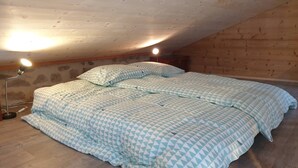 A bedroom with a sloped ceiling, a bed with patterned bedding, and two bedside lamps. - A haven of peace in Rochepaule, in the heart of Ardèche verte (Rochepaule)