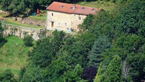 A stone building with a red-tiled roof, surrounded by dense greenery and trees. - A haven of peace in Rochepaule, in the heart of Ardèche verte (Rochepaule)
