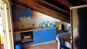 A kitchen with blue cabinets, a wooden ceiling, and a tiled backsplash. - Beachfront penthouse with panoramic terrace and direct beach access (Capo d'Orlando)