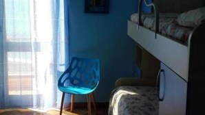 A room with a bunk bed, a blue chair, and a window with sheer curtains. - Beachfront penthouse with panoramic terrace and direct beach access (Capo d'Orlando)