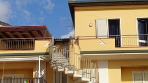 A yellow building with a balcony and a staircase leading to an upper floor. - Beachfront penthouse with panoramic terrace and direct beach access (Capo d'Orlando)
