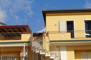 Ein gelbes Gebäude mit Balkon und einer Treppe, die zu einer oberen Etage führt.