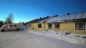 A snow-covered parking area with a yellow building that has multiple windows and a metal roof. - Åre Vandrarhem (Duved)