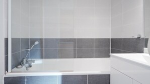 A modern bathroom with a bathtub, a shower, and a sink. - Charming Studio - Sleeps 2 - Close to the sea (Agde)