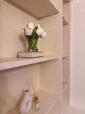 A shelf with a vase of white flowers and a reed diffuser. - Cosy Soho Flat - Steps from Covent Garde (London)