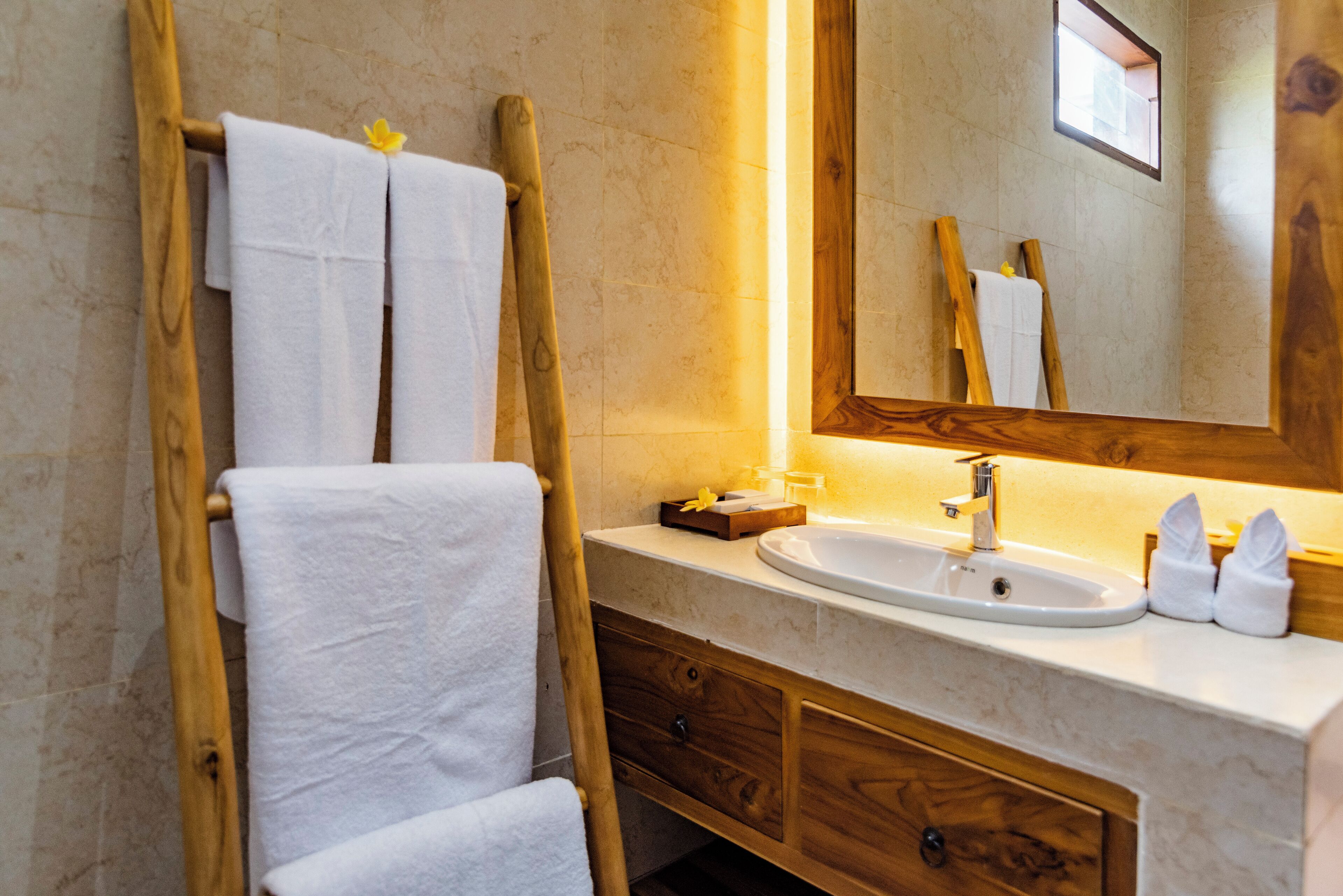 A bathroom with a wooden towel rack, a sink, and a mirror.
