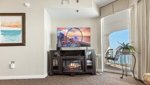 Ein Wohnzimmer mit Kamin, einem an einem Holzkasten montierten Fernseher und einem Balkon mit Meerblick.