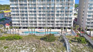 Ein mehrstöckiges Hotel mit Balkonen, einem Poolbereich und Blick auf den Strand.