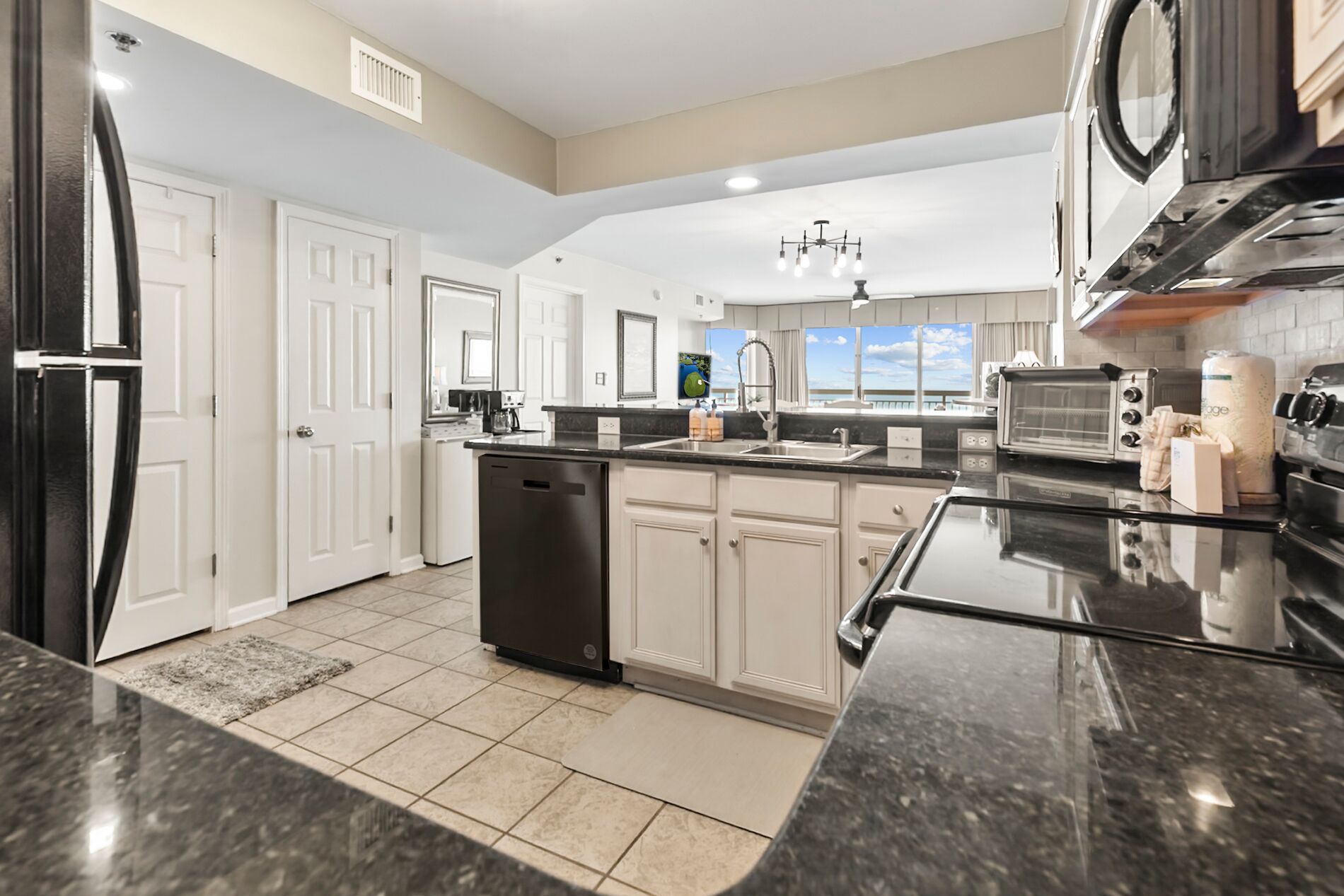 A modern kitchen with a central island, stainless steel appliances, and a view to the outside.