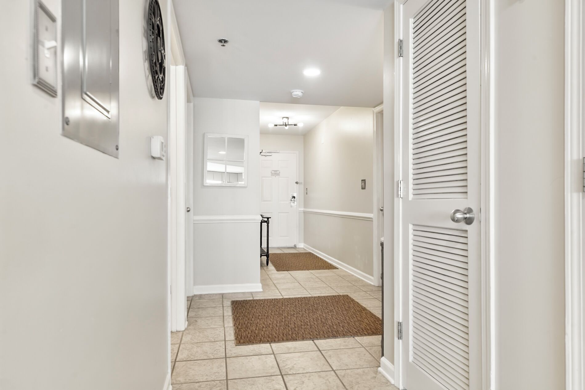 A hallway with a door on the right, a small table, and a wall-mounted light fixture.
