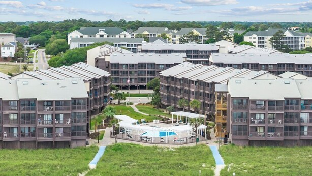 Ein mehrstöckiges Hotel mit Innenhof, Außenpool und Zugang zum Strand.