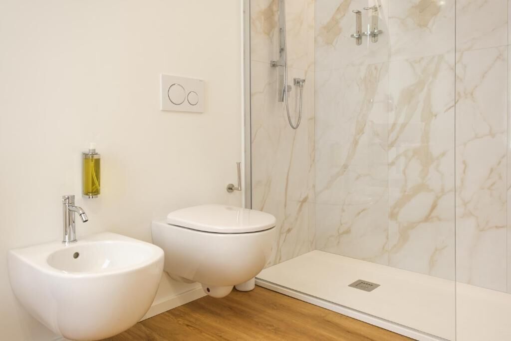 A bathroom with a bidet, a toilet, and a shower with a glass door.