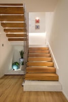 Un escalier moderne avec des marches en bois et une rampe en métal, menant à un palier où se trouve un luminaire.