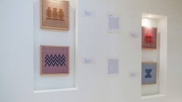 Eine Galerie mit gerahmten Kunstwerken, darunter geometrische Muster und ein sternförmiges rotes Design.
