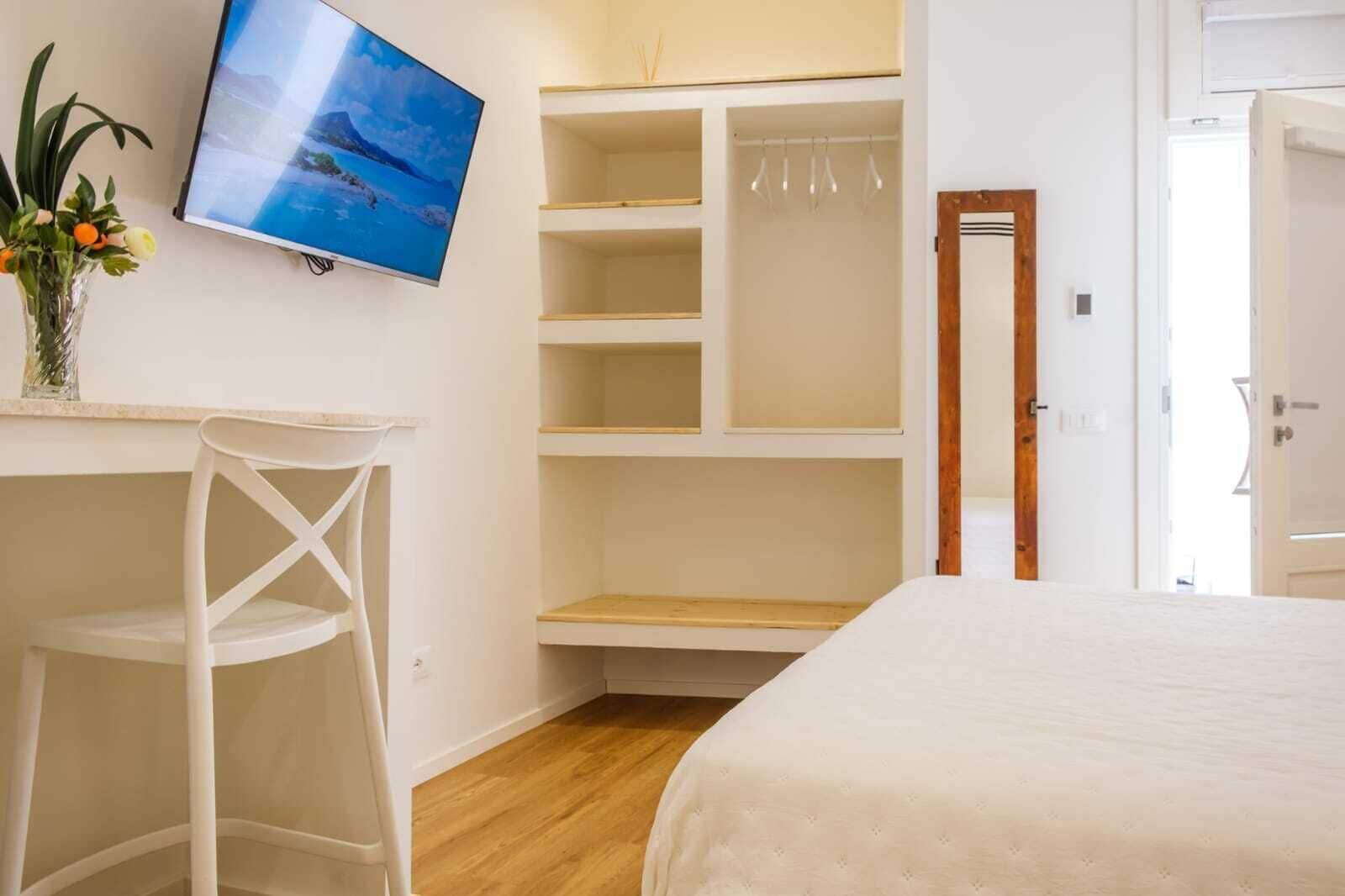 Un dormitorio con cama, escritorio, silla, televisor y armario.