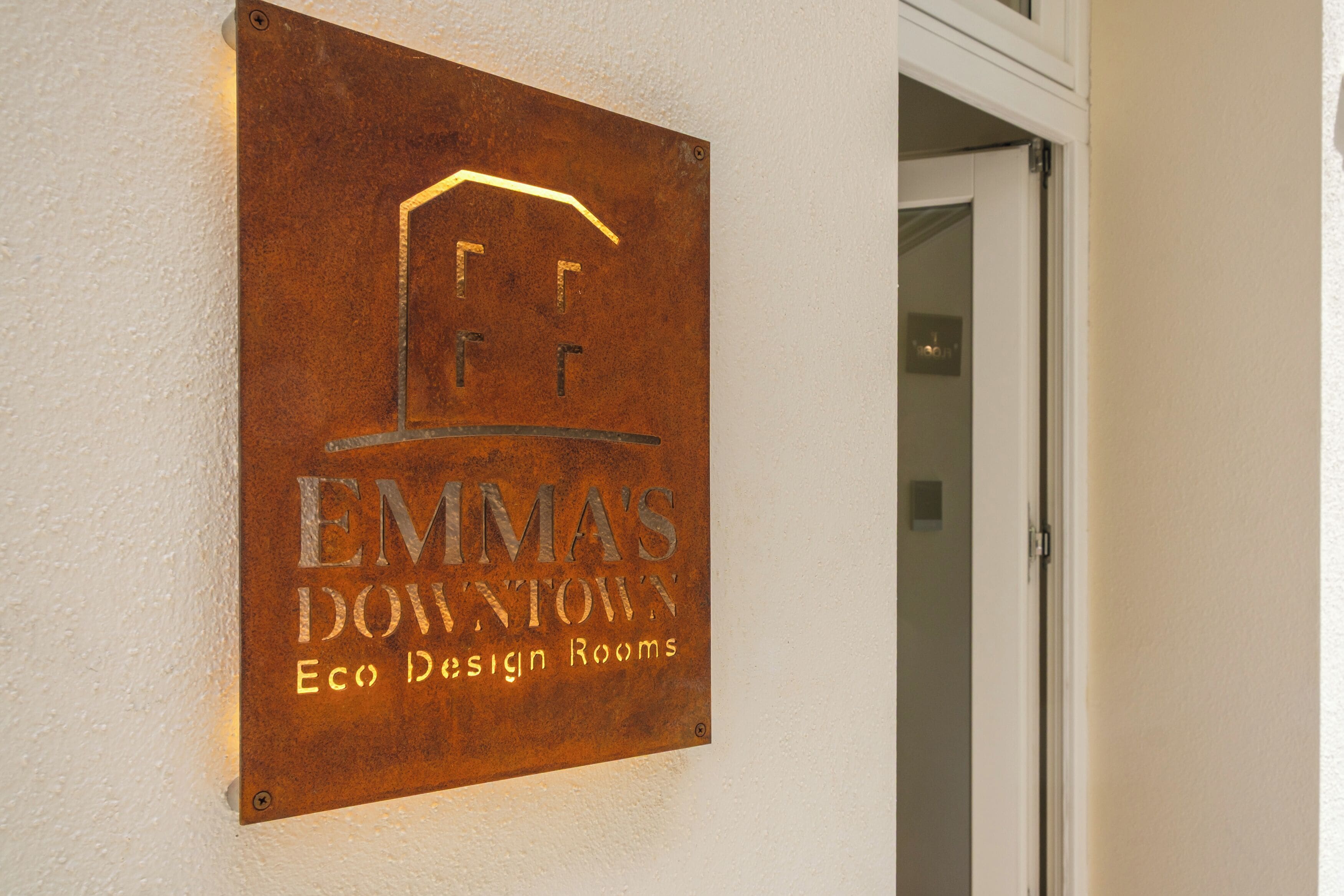 A sign for "EMMA'S DOWNTOWN Eco Design Rooms" mounted on a wall.