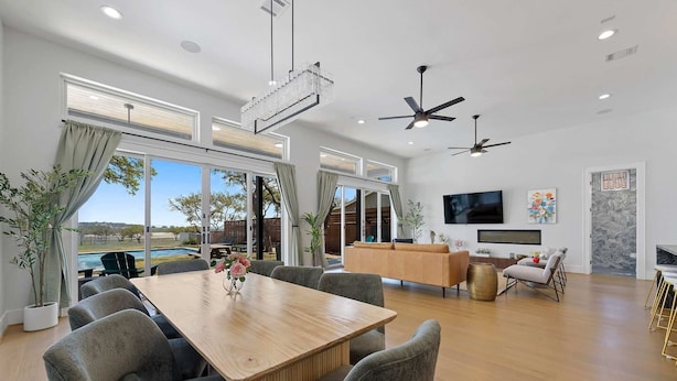 A spacious living area with a wooden dining table, grey upholstered chairs, a sofa, a TV, and a large window with a view. - Mstr dwn! Pool, DiscGolf, ZipLine, FirePit (Canyon Lake)