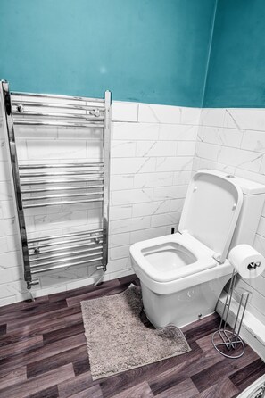 A bathroom with a toilet, a towel rack, and a rug. - Private entrance, full kitchen and quick tram ride to Manchester (Chorlton-cum-Hardy)