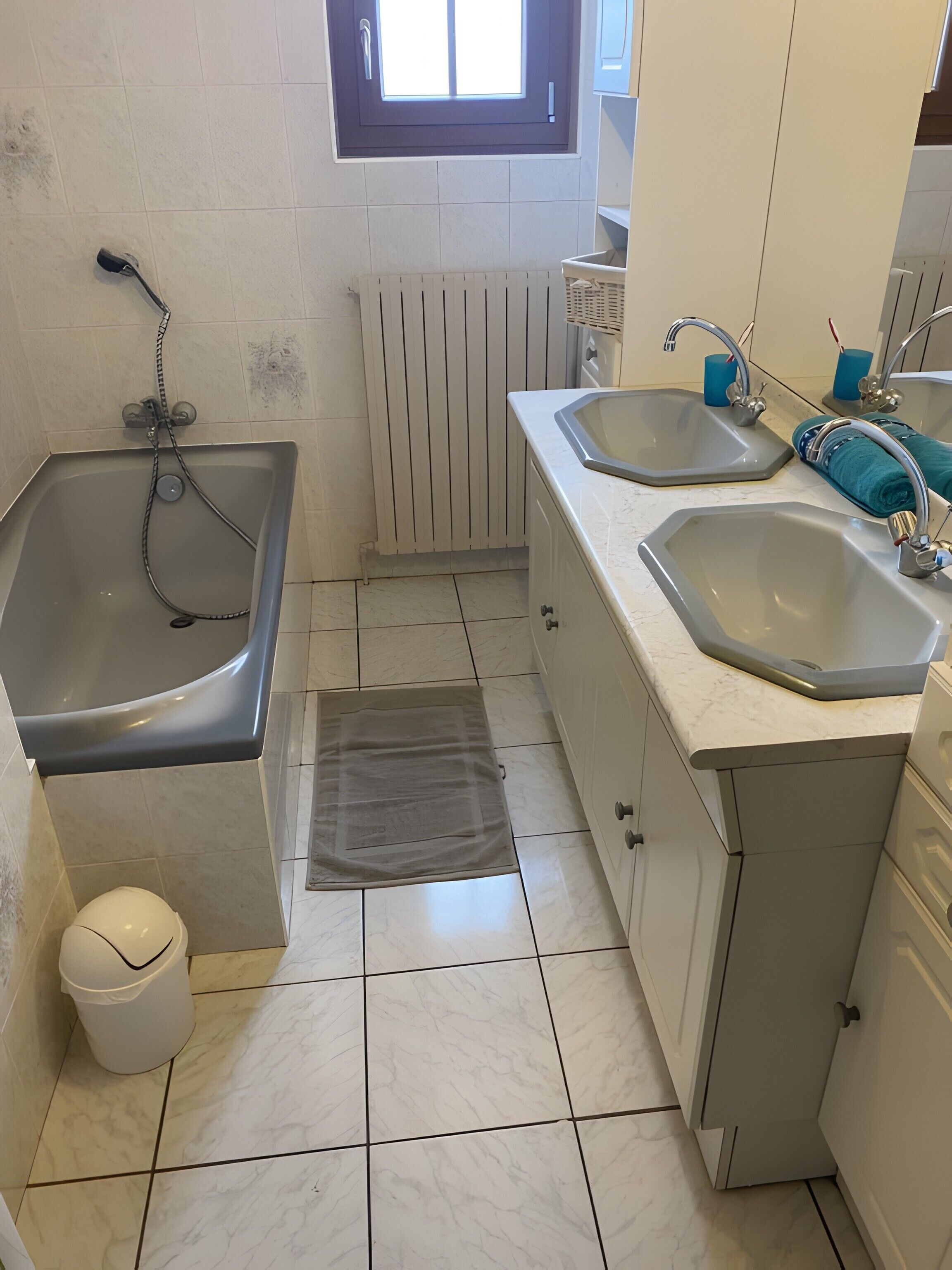 Une salle de bain avec une baignoire, deux lavabos, des toilettes et une fenêtre.