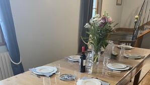 Een eettafel gedekt met borden, glazen en een fles, met een bank en stoelen eromheen.