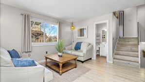 Ein modernes Wohnzimmer mit einer Couch, einem Couchtisch und einer Treppe, die zu einer weiteren Ebene führt.