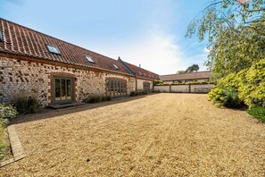 A stone building with a gravel driveway and a clear sky. - 3 Marshland Barns - sleeps 8 guests  in 4 bedrooms (Titchwell)