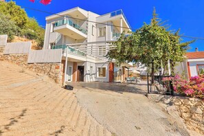 A modern two-story building with balconies, a stone retaining wall, and a paved driveway. - Villa Mevsim – 6 bedroom Luxury Sea View Retreat with Private Pool (Antalya)
