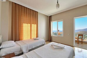 A hotel room with two beds, a large window with a view, and a balcony with a chair. - Villa Mevsim – 6 bedroom Luxury Sea View Retreat with Private Pool (Antalya)