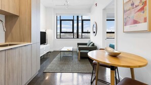 Una cucina moderna con mobili in legno, un'area pranzo con un tavolo rotondo e un'ampia finestra con vista sulla città.