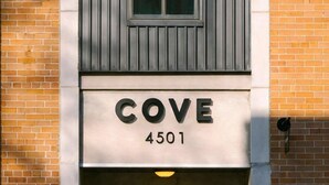Entrada de um edifício com uma placa indicando "COVE 4501" acima de uma porta de vidro com puxador.