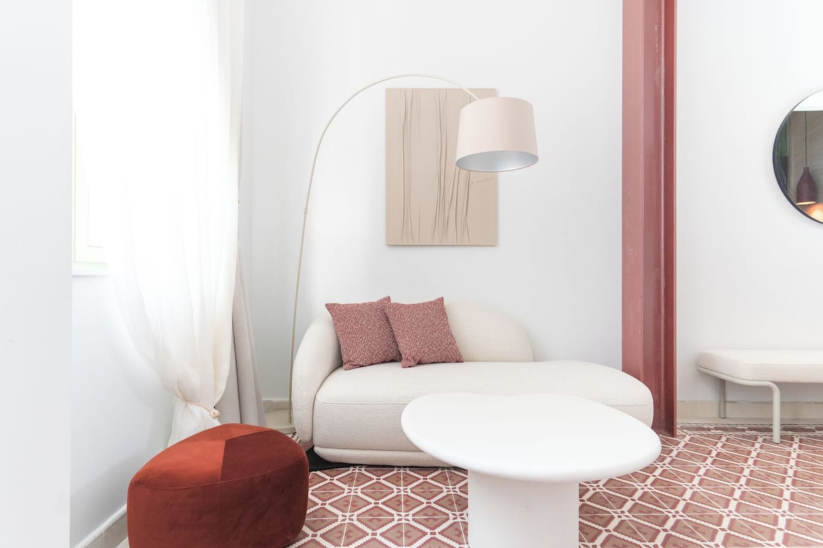 A modern living room with a sofa, a round table, a floor lamp, and a wall-mounted mirror.