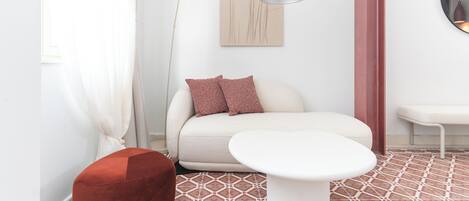 A modern living room with a sofa, a round table, a floor lamp, and a wall-mounted mirror.