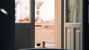 A view through a partially open door, revealing a balcony with a small table and a potted plant. - Maison Dumah (Siracusa)