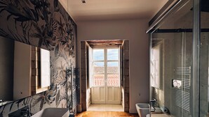 A modern bathroom with a large bathtub, a glass shower enclosure, and a wooden floor. - Maison Dumah (Siracusa)