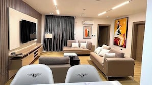 Een moderne woonkamer met een flatscreen televisie, een eettafel met stoelen, een zithoek en kunst aan de wanden.