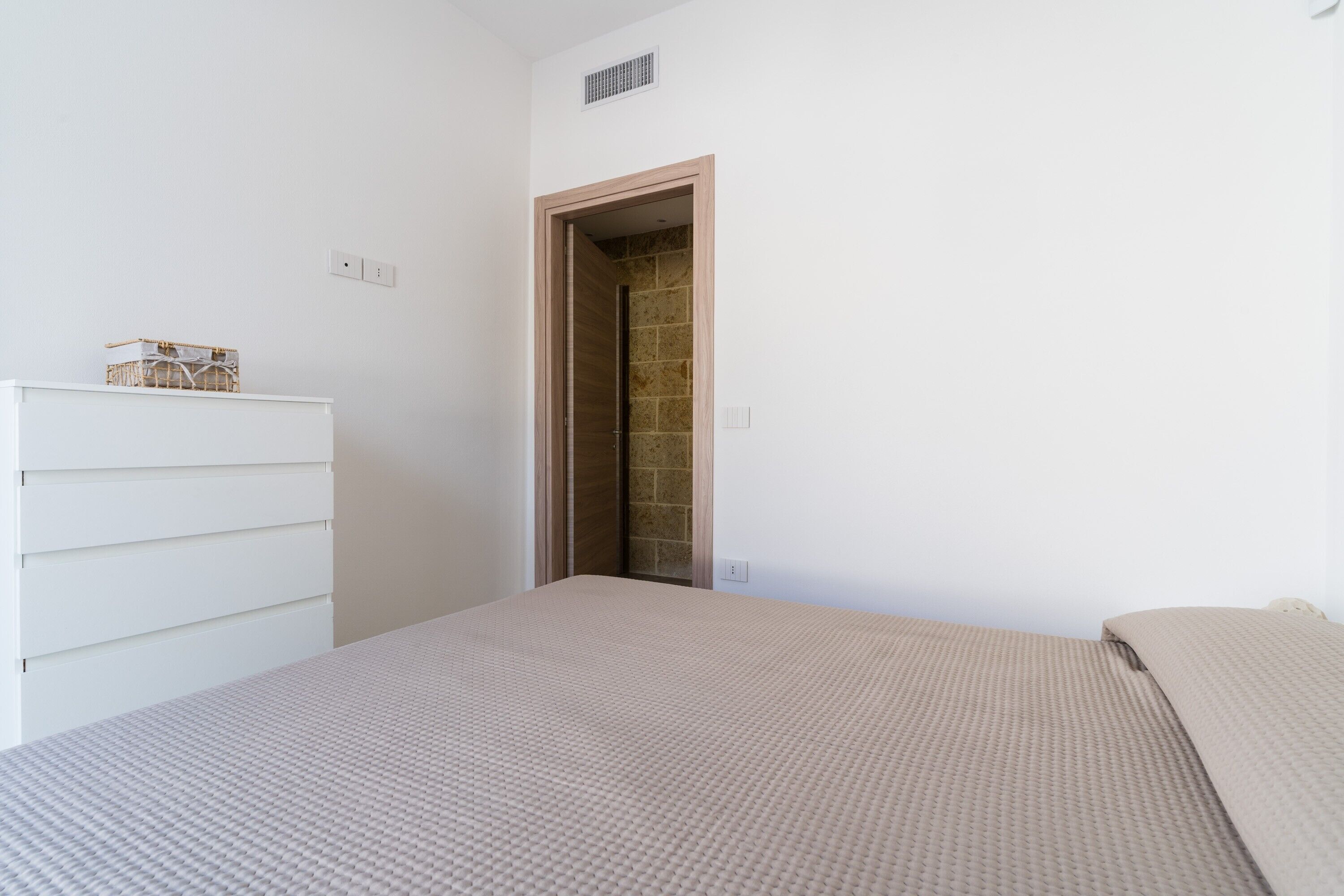 Une chambre à coucher comprenant un lit, une commode et une porte donnant sur une salle de bain.
