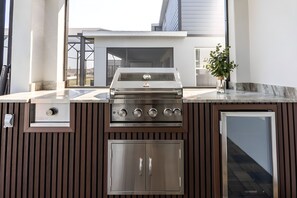 Eine Außenküche mit integriertem Grill, Spüle und Stauraumschrank.