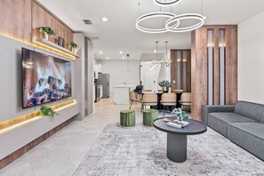 Ein modernes Wohnzimmer mit einem Flachbildfernseher, einem runden Couchtisch und einem grauen Sofa.