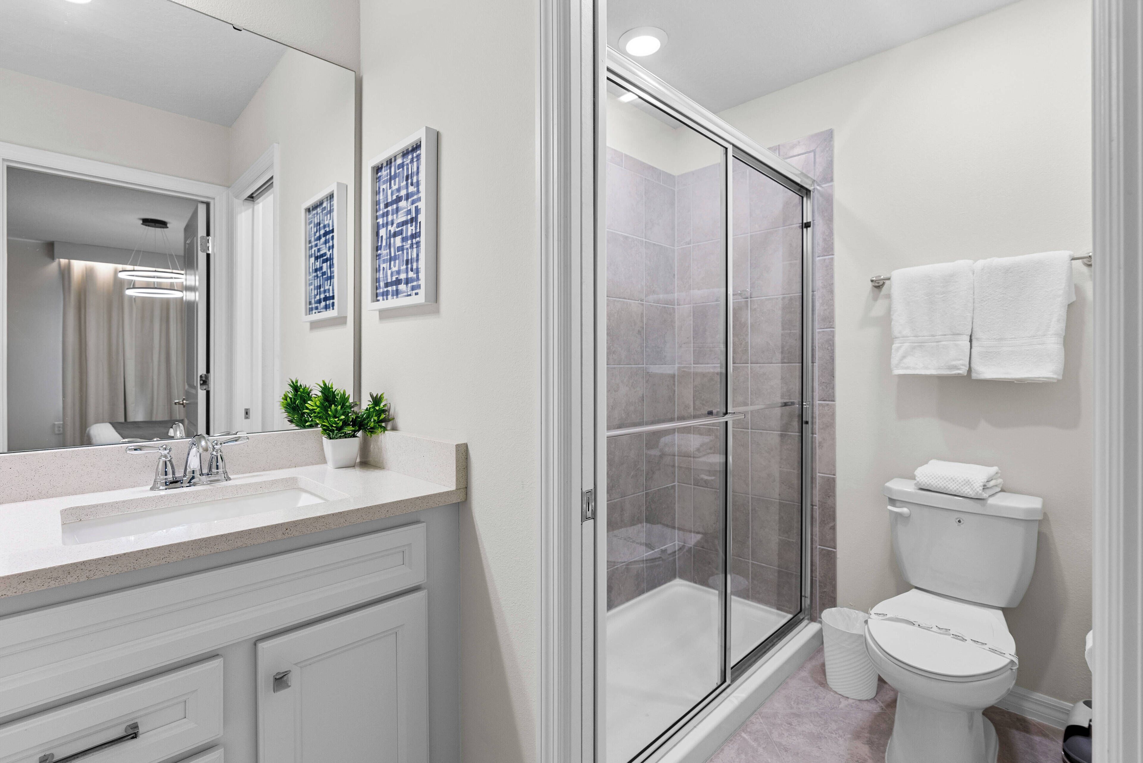 A modern bathroom with a glass-enclosed shower, a white sink, and a toilet.