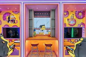 A room with a Simpsons-themed wall, a bar area with stools, and a TV screen. - 9BR house sleeps 18 with spa and pool table (Kissimmee)
