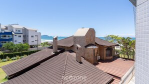 A rooftop with a tiled roof, a brick building, and a view of the sea. - Apartment With BBQ in Condo With Pool Eaf0404 (Florianópolis)