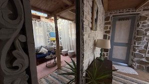 A rustic stone-walled room with a blue sofa, a small table with a lamp, and a wooden door. - Enjoyable 1-bedroom bed & breakfast in charming Naggar (Naggar)