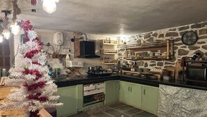 A rustic kitchen with green cabinets, a stone wall, and a white Christmas tree. - Enjoyable 1-bedroom bed & breakfast in charming Naggar (Naggar)