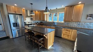 A modern kitchen with wooden cabinets, stainless steel appliances, and a central island with bar stools. - Flying Goose - newly built 4-bedroom house with incredible views in Wilmington (Wilmington)