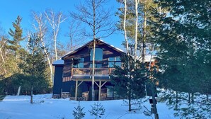 A two-story log cabin with a balcony, surrounded by snow and trees. - Flying Goose - newly built 4-bedroom house with incredible views in Wilmington (Wilmington)