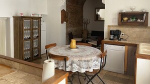 A compact kitchen with a round table, a cabinet with glass doors, and a coffee machine.