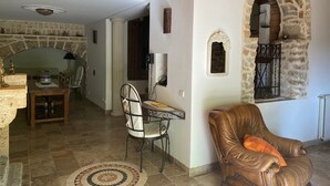A cozy living room with a stone fireplace, a dining area, and a leather armchair.