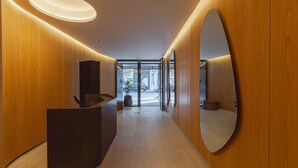 A modern reception area with wooden paneling, a reception desk, and a large mirror. - MOT Rentals + Design SohoHaus '407' - 3 pax Full Amenities (Buenos Aires)