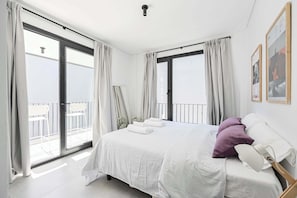 Ein Schlafzimmer mit einem Bett, weißen Vorhängen, einem Balkon und einer Deckenleuchte.