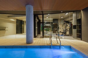 A modern indoor pool area with a wooden deck, exercise equipment, and glass walls. - MOT Rentals + Design SohoHaus 508 - 3 pax Full Amenities (Buenos Aires)